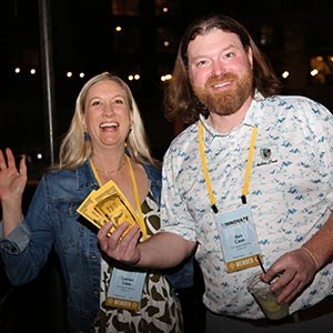 Two attendees celebrating with Plus Bucks at an evening event