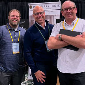 Three attendees posing at a supplier booth in the exhibit hall