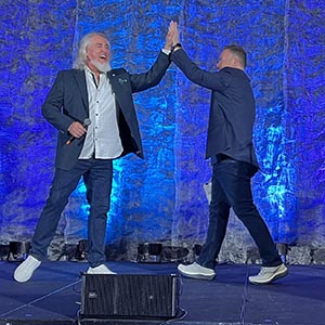 Two presenters sharing a high five on stage at the general session