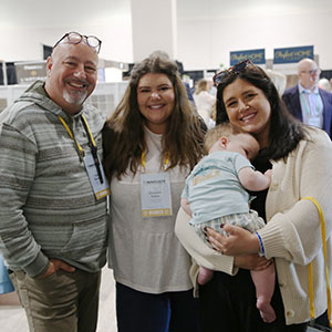 Smiling attendees, including a baby, in the exhibit hall